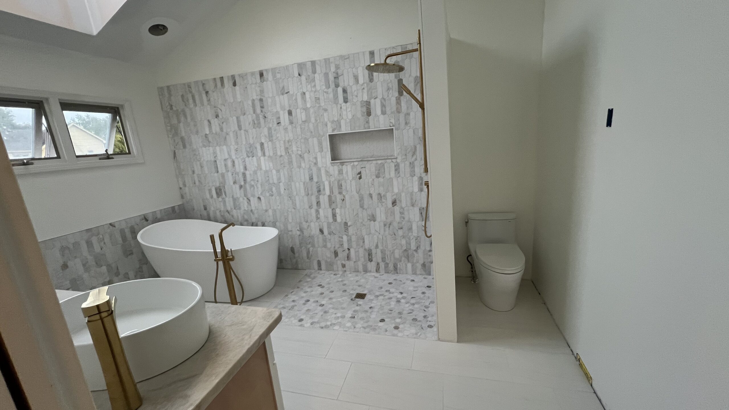 Home Bathroom with freestanding tub, tiled shower, and gold fixtures